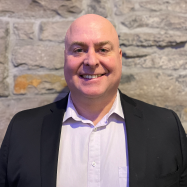 Peter Saunders smiling in front of stone wall