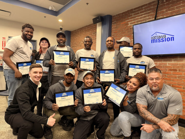 A group of 10 graduates of the MSTP pose with their certificates and two staff members at their graduation. Everyone has a big smile and looking proud.
