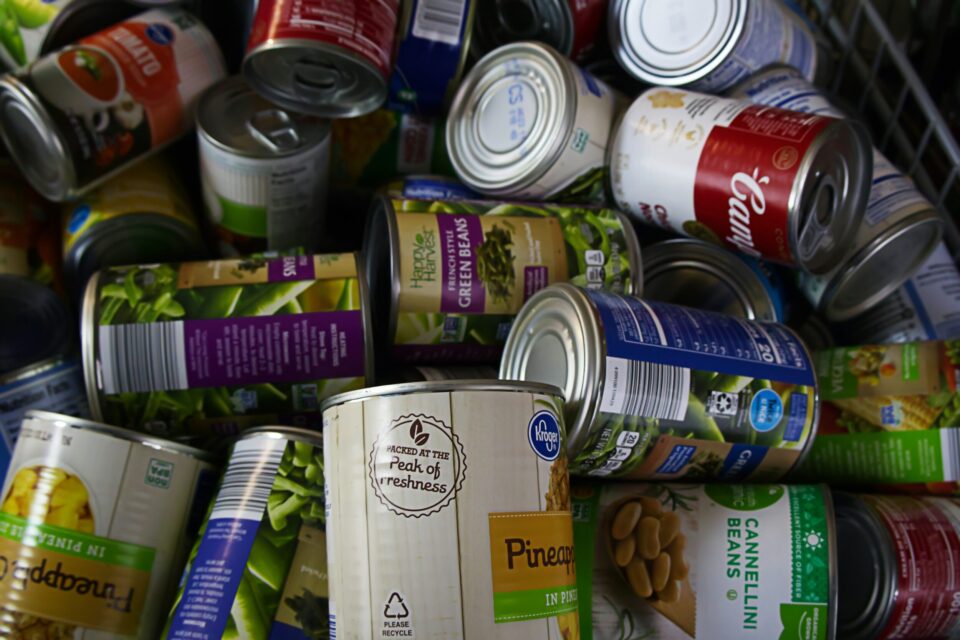 A pile of canned goods, including pineapple, green beans, and soup, in various colorful labels.