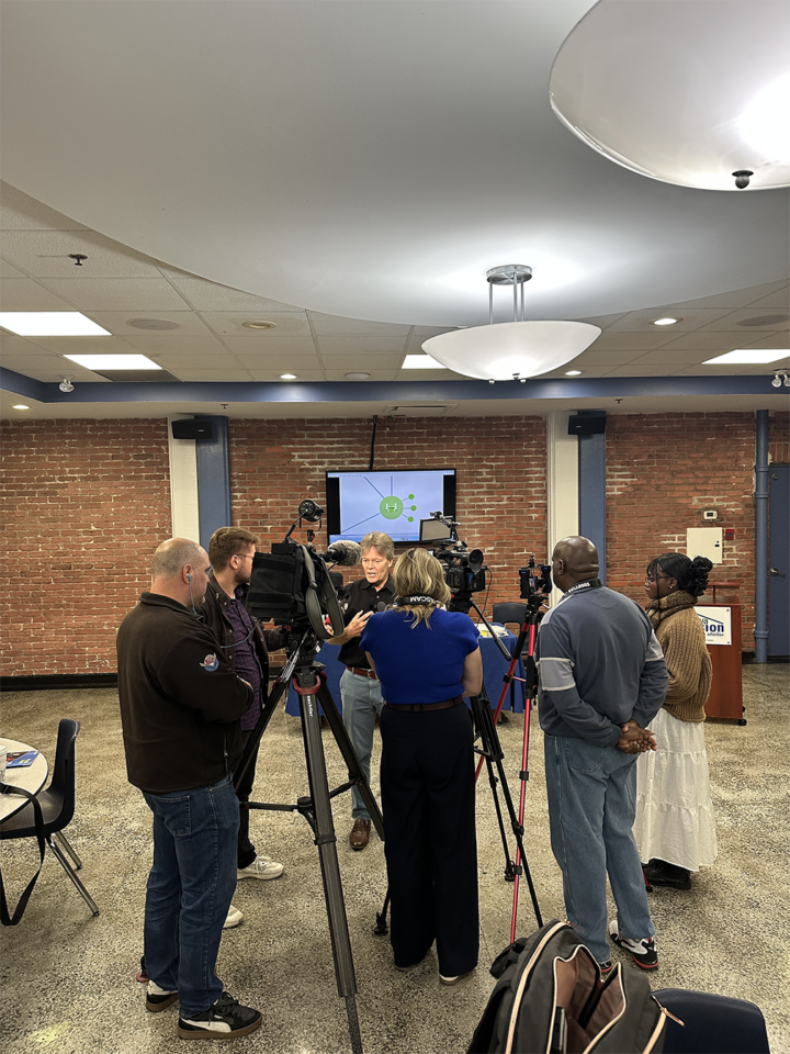 A man speaks to reporters as he stands in front of three video cameras.